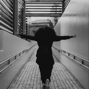 A person with curly hair walks down a ramp